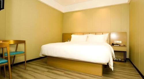 a bedroom with a large white bed and a table at Borrman Hotel Xiamen Xiang'an Maxiang in Xiamen