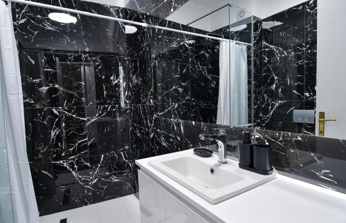 un bagno piastrellato nero con lavandino e specchio di Zeusplace Black and White Retreat a Kateríni