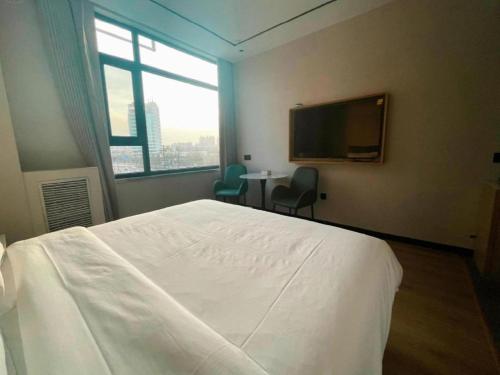 a bedroom with a bed and a tv and a table at GreenTree Inn Datong YundinGYAyuan Express Hotel in Datong