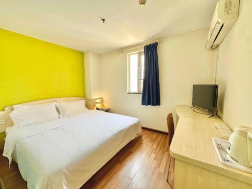 a bedroom with a white bed and a television at 7 Days Inn Guangzhou Zoo Huanghuagang Metro Station in Guangzhou