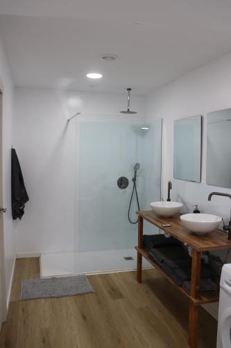 Un baño con dos lavabos y una ducha de cristal. en fuga romantica, en Benisuera