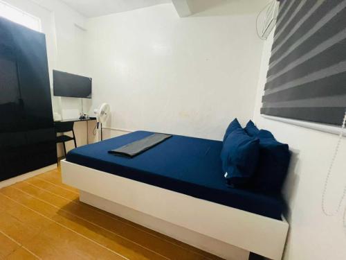 ein Zimmer mit einem Bett mit blauen Kissen und einem Schreibtisch in der Unterkunft T&A Building in Manila