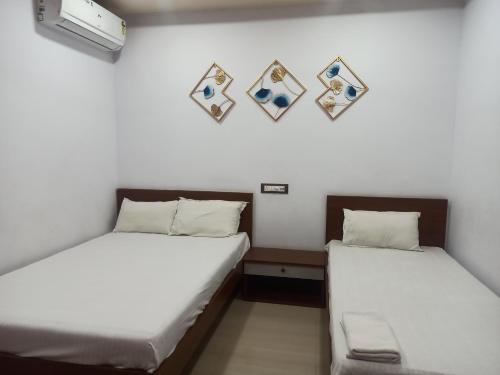 two beds in a room with pictures on the wall at Ashirbad Lodge in Lokpriya Gopinath Bordoloi International