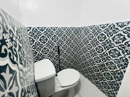 ein Badezimmer mit Toilette und einer schwarz-weiß gemusterten Wand in der Unterkunft T&A Building in Manila