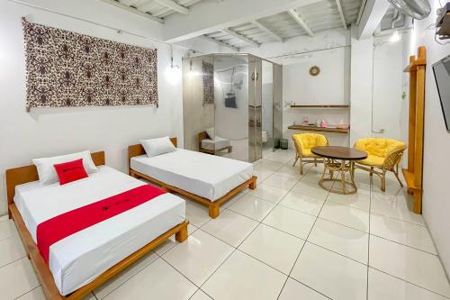 a bedroom with two beds and a table and chairs at RedDoorz Syariah at Jalan RA Kosasih Sukabumi in Sukabumi