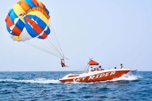 a red and white boat in the water with a parachute at DoubleTree by Hilton Resort & Spa Marjan Island in Ras al Khaimah