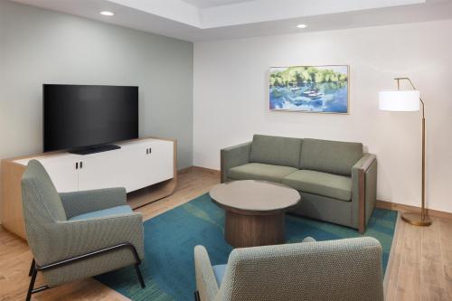 a living room with a couch and a tv and chairs at Embassy Suites San Marcos Hotel Conference Center in San Marcos