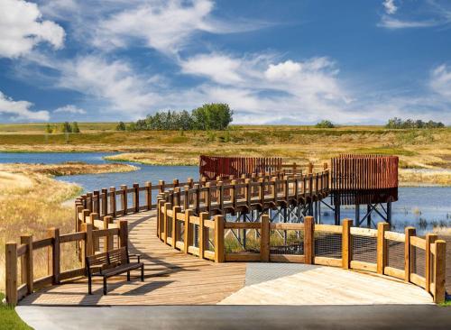 a wooden bridge over a river with benches on it at The SuiteLife, Calgary in Calgary