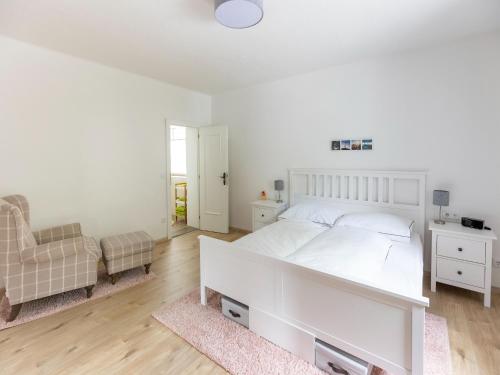 a white bedroom with a large white bed and a chair at Gailtaler apartment at an excursion location in Kötschach