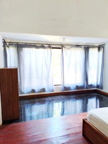 a bedroom with a bed and a window with white curtains at Kondo Villa in Labuhan Pandan