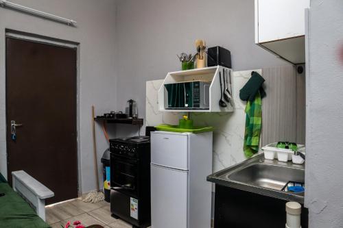 a small kitchen with a microwave on top of a refrigerator at Emerald Green Family Haven! in Rustenburg