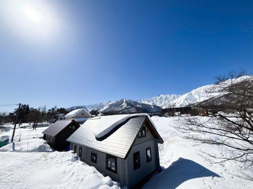 a house covered in snow with mountains in the background at el green log in Hakuba