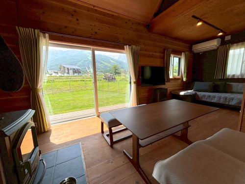 a living room with a table and a large window at el green log in Hakuba