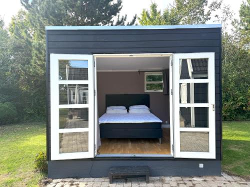 VejbyにあるTennis, spa outside & inside and sauna - Tisvildelundの白い窓とベッドのある黒い小さな家