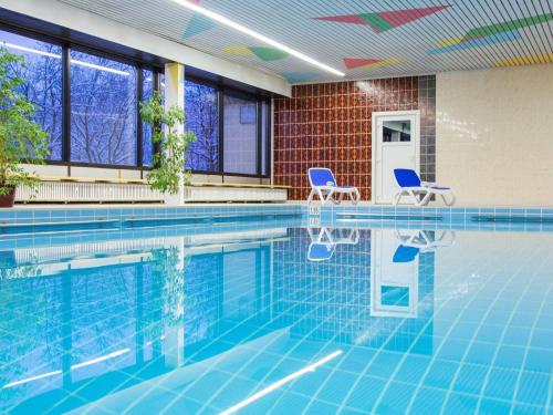 a swimming pool with two chairs in a building at Inviting apartment in Freyung with sauna & indoor pool in Freyung
