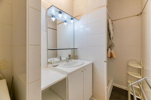 ein weißes Badezimmer mit Waschbecken und Spiegel in der Unterkunft Vacances de rêves - Amoureux in Chamrousse