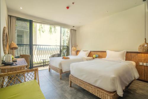 two beds in a room with a balcony at The Signature Hotel Nha Trang in Nha Trang