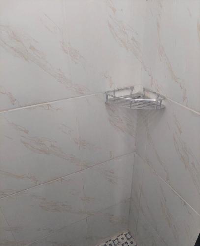 a bathroom with white marble walls and a shelf on the wall at JANNAH Syariah in Takengon