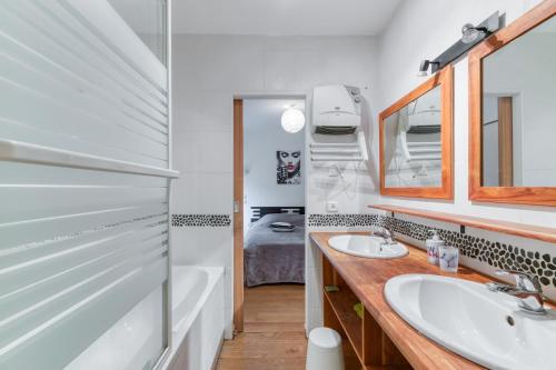 ein Badezimmer mit zwei Waschbecken und einer Badewanne und einem Spiegel in der Unterkunft Vacances de rêves - Gaboureaux in Chamrousse