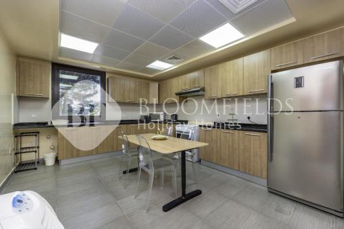 a kitchen with a table and a refrigerator at Bloomfields Luxurious 2BR Maid Room in Fujairah