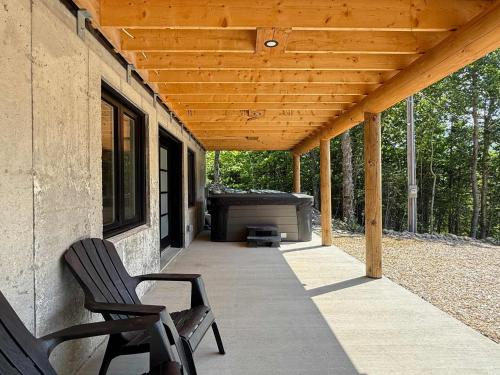 a covered porch with two chairs and a grill at Spa Game Room Absolute Comfort - Le Commandant in Saint-Philémon