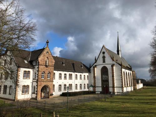 a large white building with a church with a steeple at Dormio Hotel Der Seehof in Heimbach
