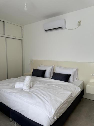 a large bed with white sheets and pillows at צליל ההר - The sounds of the mountain in Safed