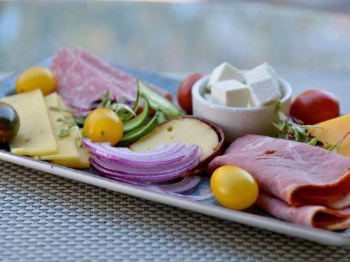 a plate of food with cheese and meats and vegetables at ANEW Hotel Hatfield Pretoria in Pretoria