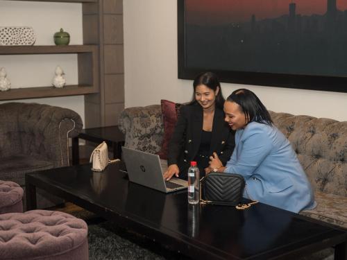 two women sitting around a table with a laptop at ANEW Hotel Hatfield Pretoria in Pretoria