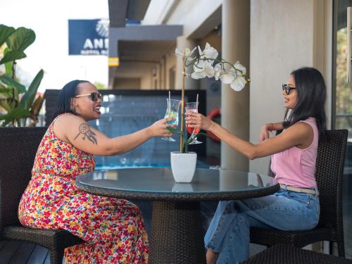 two women sitting at a table with drinks at ANEW Hotel Hatfield Pretoria in Pretoria