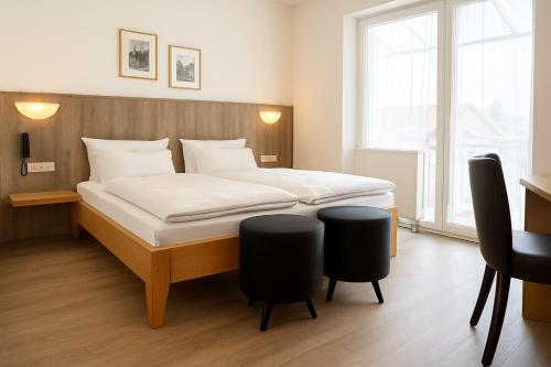 a bedroom with a bed with two black chairs at Hotel Orthwein -kostenfreie Parkplätze- in Cölbe
