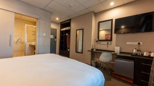 a bedroom with a large white bed and a desk at ANEW Hotel Hatfield Pretoria in Pretoria