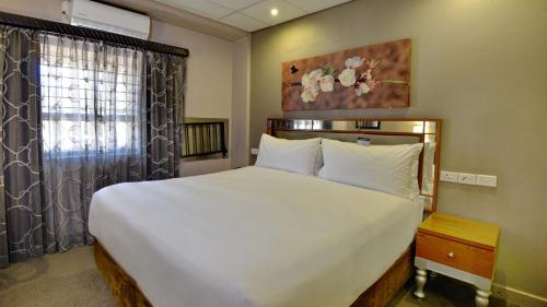 a bedroom with a large white bed and a window at ANEW Hotel Hatfield Pretoria in Pretoria