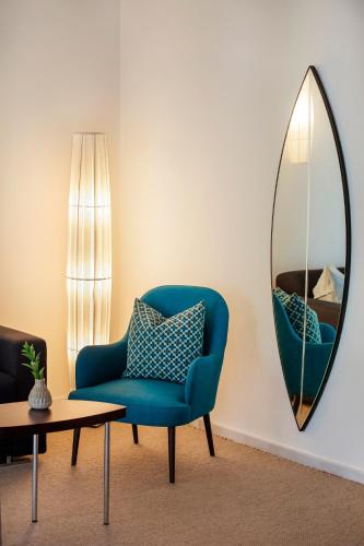 a living room with a blue chair and a mirror at Hotel Esplendido in Port de Soller