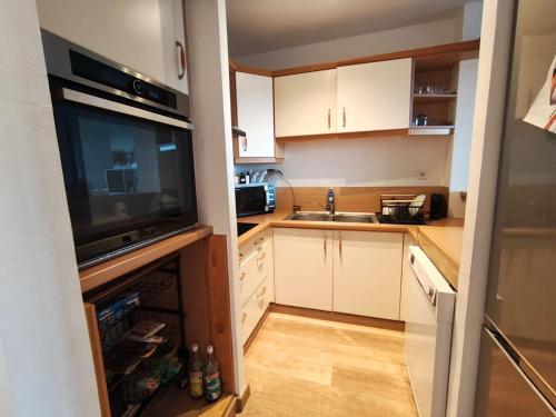 a small kitchen with white cabinets and a television at Ti kaz Galante Bel appartement avec Vue mer in Saint-Gilles les Bains