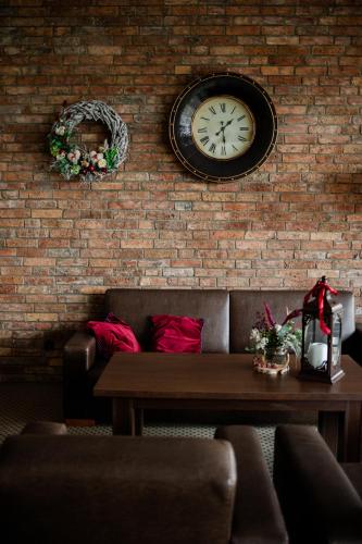 a brick wall with a clock and a table at Hotel & Restauracja Timberland in Orzesze