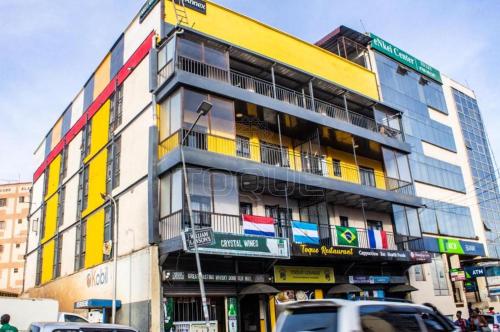 ナイロビにあるTOQUE BNB Nairobiのカラフルな窓と車が目の前に停まった建物