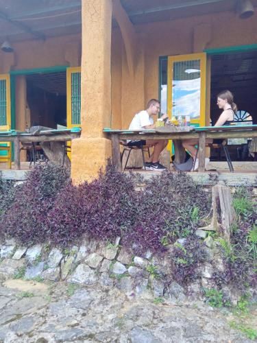 two people sitting at a picnic table in front of a building at H'mong Cổ Trấn Sapa Homestay & Restaurant in Sa Pa