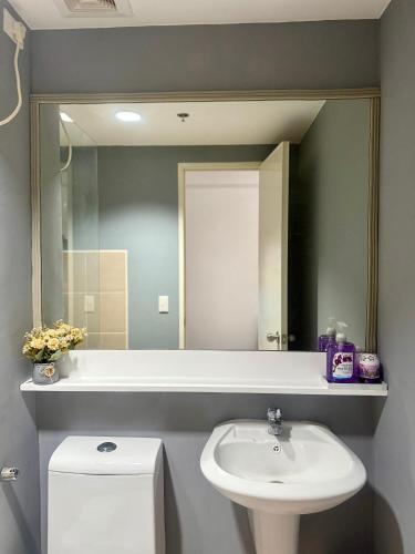 a bathroom with a sink and a toilet and a mirror at AACozyStays in Cagayan de Oro