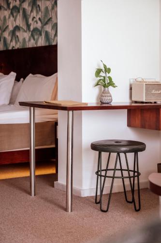 a table and stool in a room with a bed at Hotel Esplendido in Port de Soller