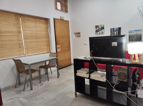 a room with a desk with a tv and chairs at jp7 Piso y parking 10min Sevilla - Zona Comercial - Joyeria - Pescaderia in Camas