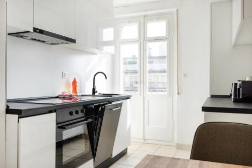 a white kitchen with a sink and a stove at Cityview Balcony - in the heart of Biel in Biel