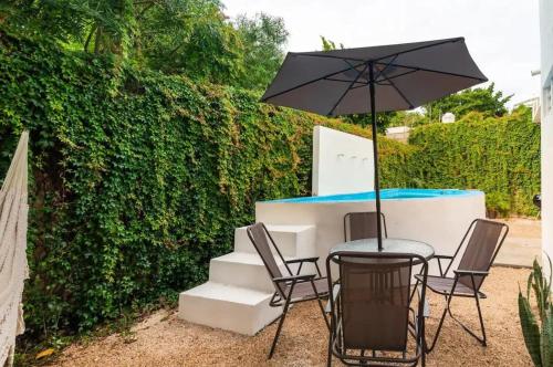 a table and chairs with an umbrella next to a hedge at Casa Maya Villa with Private Pool Bar and Parking Merida in Mérida