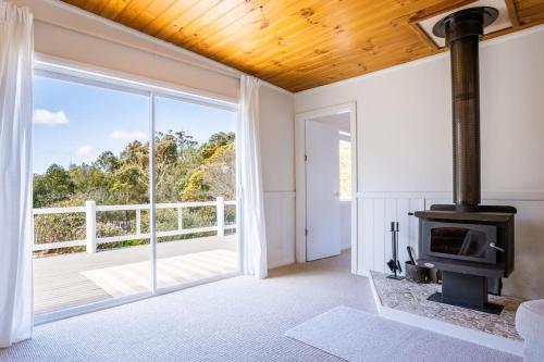 an open living room with a fireplace and a balcony at Sundrift Binalong in Binalong Bay