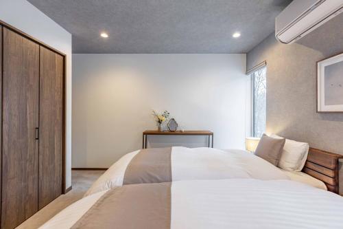 a bedroom with a large white bed and a window at 翠葉 Rusutsu in Rusutsu
