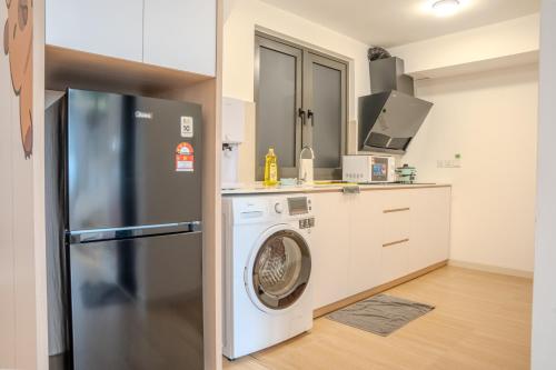 a kitchen with a refrigerator and a washing machine at Sunway Grid Loft Suite by Nest Home【Olympic Size Pool】 in Kampong Pendas