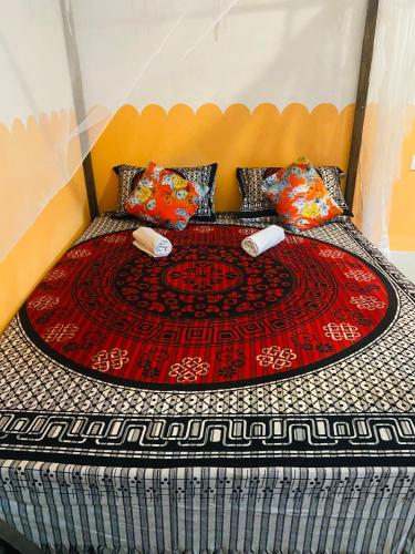 a bedroom with a bed with a red and black comforter at Ekamuthu Homestay in Dickwella
