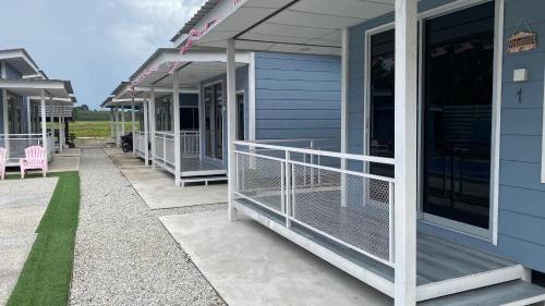 a porch of a blue house with pink chairs at Capital O 91228 Hureen Chalet Hmk in Kampung Kok Kelang