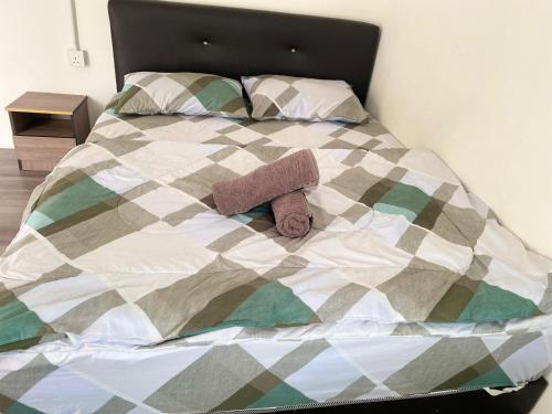 a bed with a comforter with two towels on it at Capital O 91228 Hureen Chalet Hmk in Kampung Kok Kelang