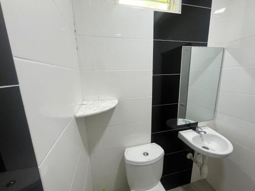 a white bathroom with a toilet and a sink at OYO 91220 D Inai Roomstay in Pantai Cenang
